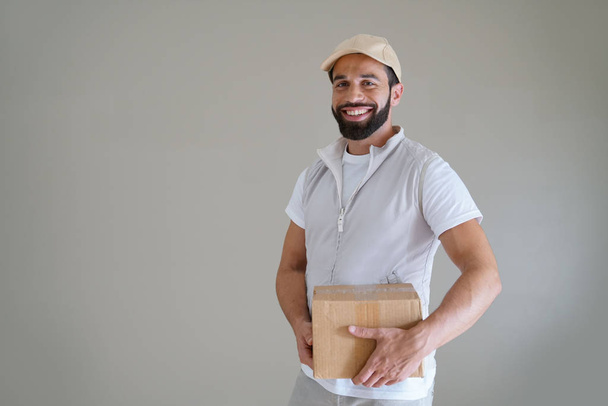 Smiling delivery man, isolated on grey background - Photo, Image