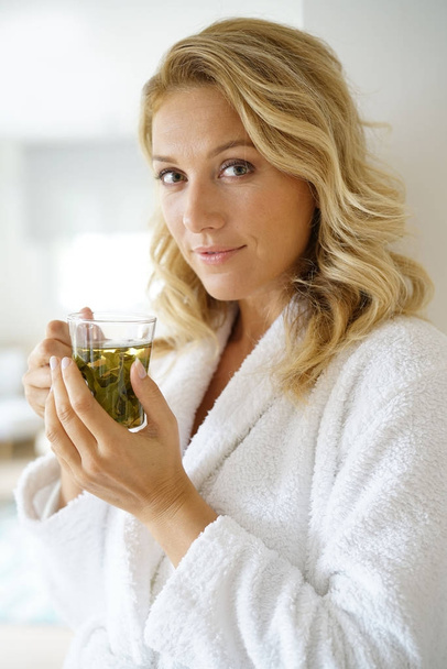 woman in bathrobe drinking infusion - Foto, Imagen