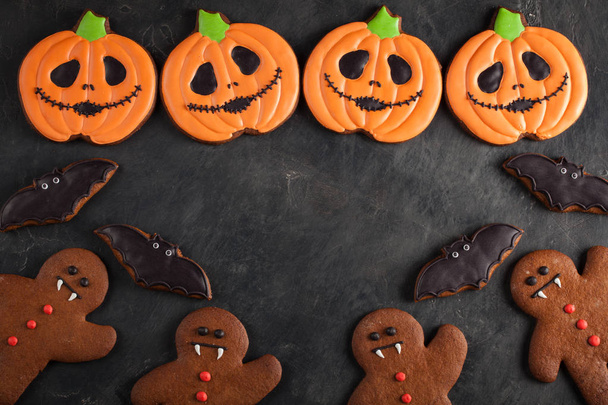 Halloween pompoen, gingerbread man en vleermuizen cookies overhead schot met kopie ruimte. Op donkere concrete achtergrond - Foto, afbeelding