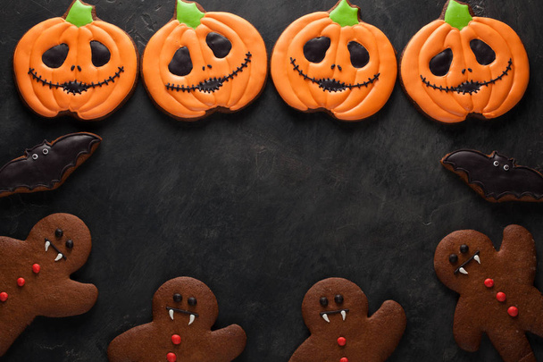 Halloween pumpkin, gingerbread man and bats cookies overhead shot with copy space. On dark concrete background - Photo, Image