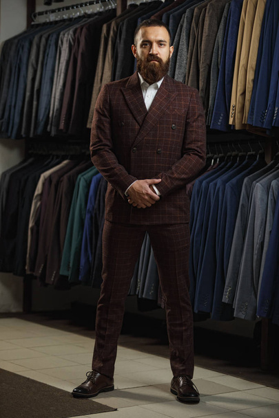 Businessman in classic vest against row of suits in shop - Fotografie, Obrázek