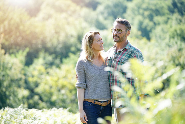 Happy mature couple walking in countryside on sunny day - Foto, imagen