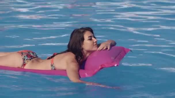 Beautiful young woman relaxing in swimming pool in summer, lying on inflatable Lounge. Summer time - Video