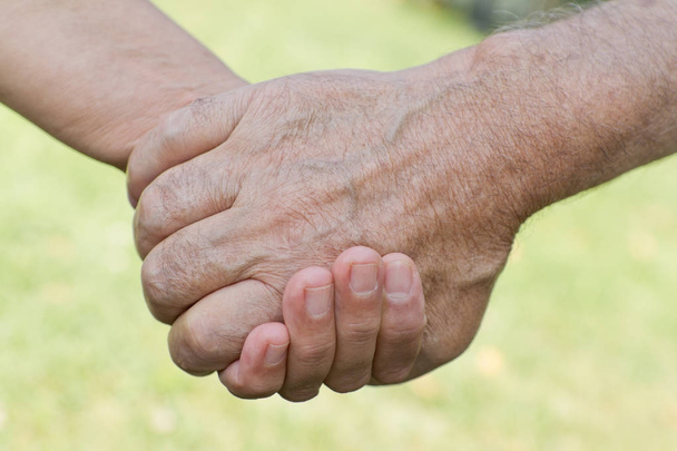Teenage boy holding senior mans hand  - Photo, Image