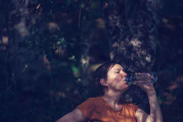 Жінка п'є воду на відкритому повітрі
 - Фото, зображення