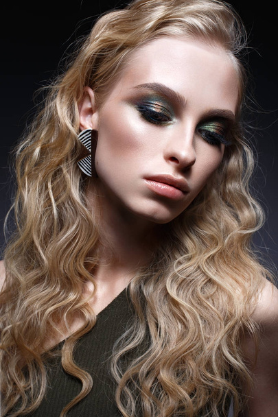 Young girl with curls and bright creative make-up. Beautiful model in earrings and green top. Beauty of the face. - Foto, Imagem