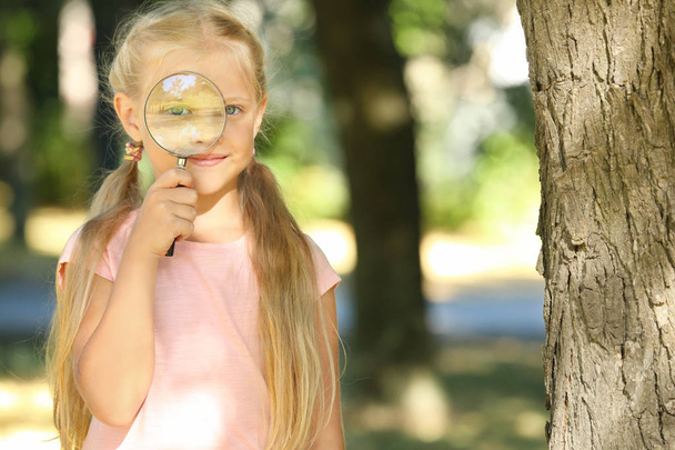Cute little girl with magnifying glass outdoors - Valokuva, kuva