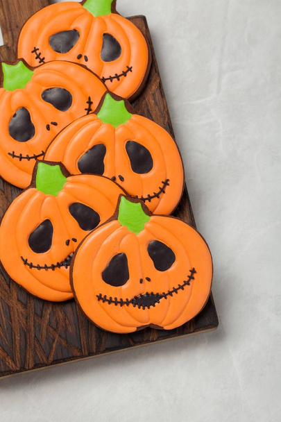 Homemade ginger cookies in the shape of pumpkins for Halloween. On the lighter concrete background. Top view - 写真・画像