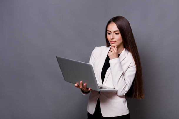 Pensive business woman with laptop on gray background - Foto, Imagem