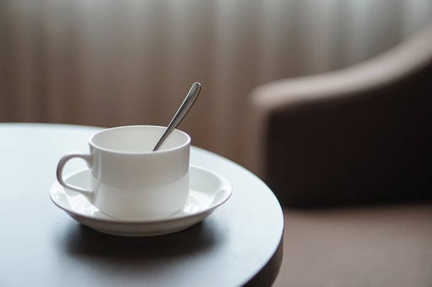 witte koffiekopje op de tafel door een banklaag in hotelkamer - Foto, afbeelding