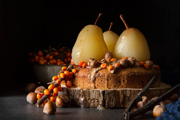 Autumn meal. Pie with pears, sea buckthorn and nuts. Dark backgr - Fotó, kép