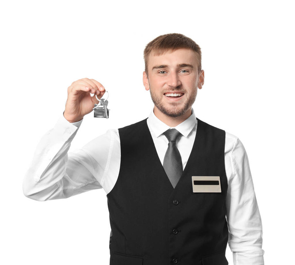 Male hotel receptionist with room key on white background - Zdjęcie, obraz
