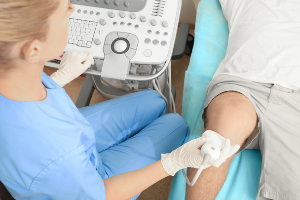 Doktor vedení ultrazvukové vyšetření pacienta koleno v klinice - Fotografie, Obrázek