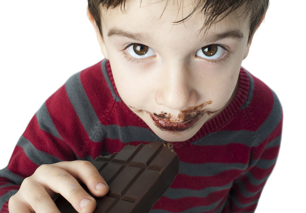 Smiling little boy eating chocolate - Фото, изображение