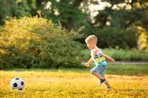 Cute boy playing football in park on sunny day - Foto, Imagen