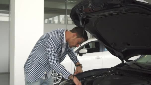 Der neue Besitzer des Autos studiert die Details in einer offenen Motorhaube - Filmmaterial, Video