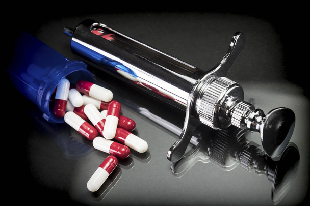 Some red and white capsules  out of a boat together with syringe - Photo, Image