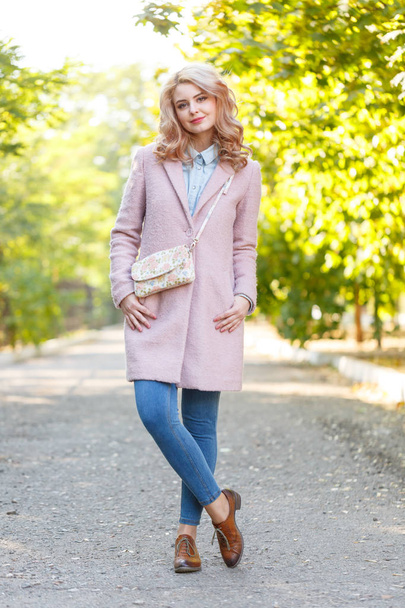 Portrait of a young beautiful girl in a pink coat. In the park. - Foto, Imagem
