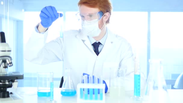 Научный сотрудник рассматривает голубое решение в пробирке в лаборатории
 - Кадры, видео