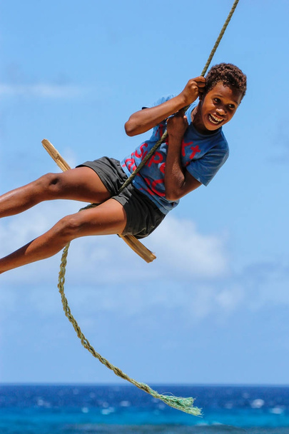 LAVENA, FIJI - NOVEMBER 27: Unidentified boy swings on a rope sw - 写真・画像