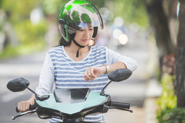 Woman looking at watch on motorbike - Zdjęcie, obraz