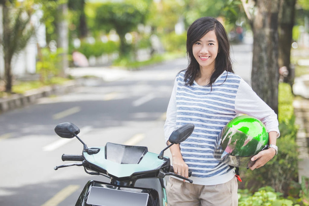 Smiling woman standing beside motorbike - Foto, Imagen