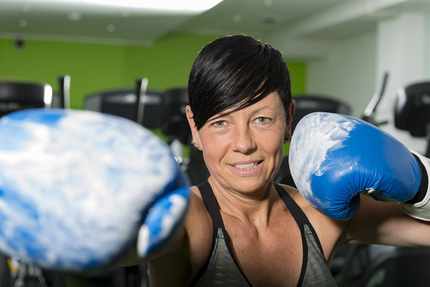 Kobieta w rękawicach bokserskich w siłowni Swinging Punch - Zdjęcie, obraz