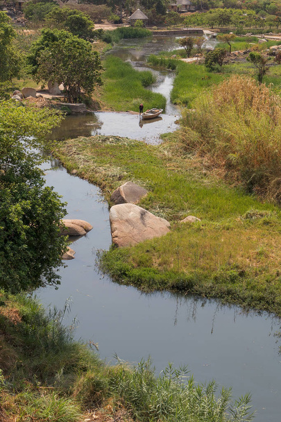 άπταιστα ποταμού με βράχια, βλάστηση, ψαράς και βάρκα στο afric - Φωτογραφία, εικόνα