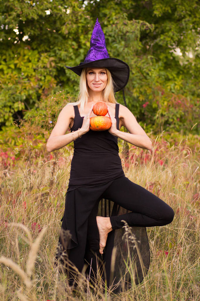 Směje se žena v kostýmu čarodějnice cvičení jógy - Fotografie, Obrázek