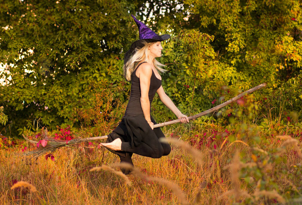 Chica feliz en traje de bruja vuela en palo de escoba
 - Foto, Imagen
