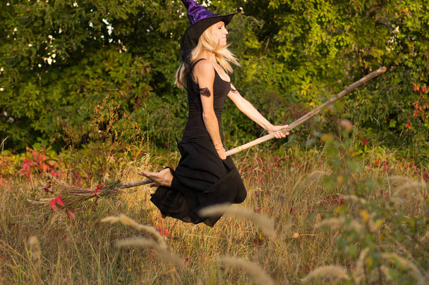 Active dziewczyna w stroju czarownica leci na miotle - Zdjęcie, obraz