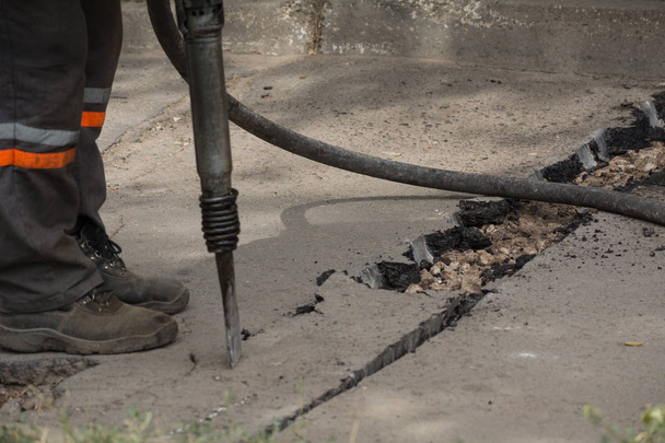 Male worker using jackhammer pneumatic drill machinery on road repair. - Photo, Image
