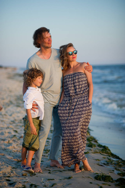 La giovane famiglia ammira un tramonto sulla costa del mare
. - Foto, immagini