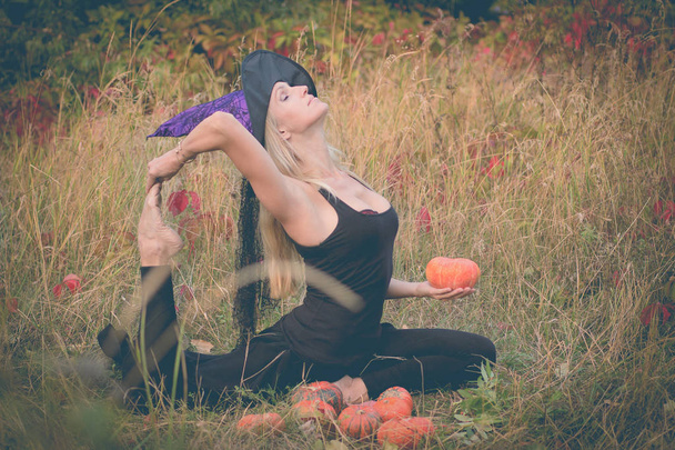 Dospělé ženy v kostýmu čarodějnice cvičení jógy - Fotografie, Obrázek