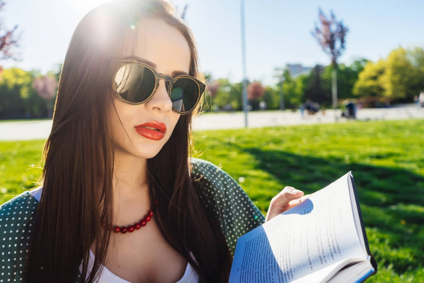 Fashion studentwith glasse  reading book outside,homework,studying.  - Zdjęcie, obraz