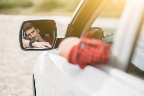 Человек смотрит в боковое зеркало автомобиля
 - Фото, изображение
