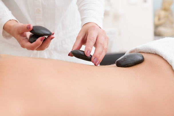 piedras calientes se ponen en una espalda de mujer para un masaje en un spa
 - Foto, Imagen