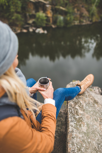 woman with cup of tea sitting on rock - Photo, Image