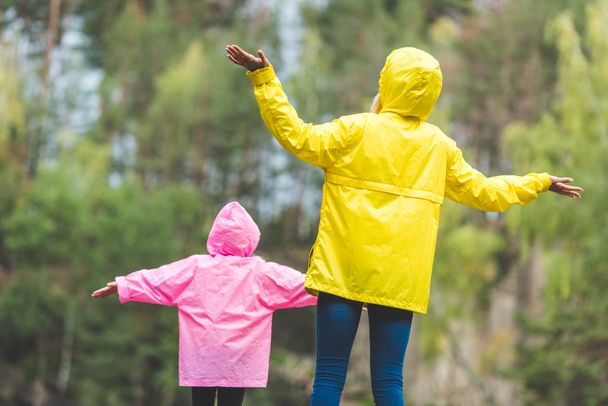 family in raincoats with outstretched arms - Foto, afbeelding