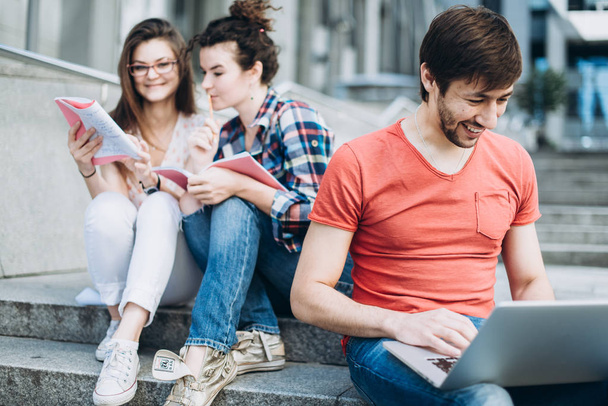 Young smart people are using gadgets and smiling while studying - Foto, afbeelding