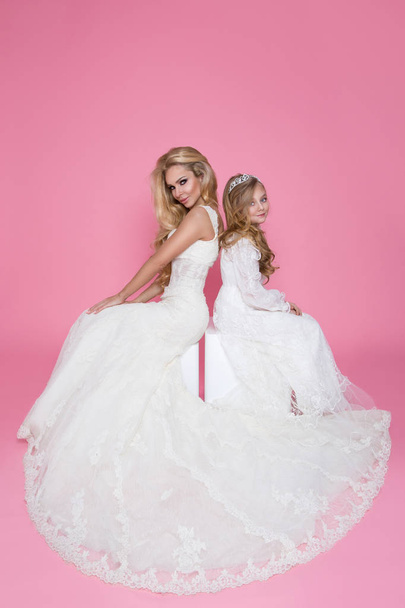 Beautiful blonde female model, mother with blonde daughter in dresses. They have beautiful wedding dresses - Photo, Image