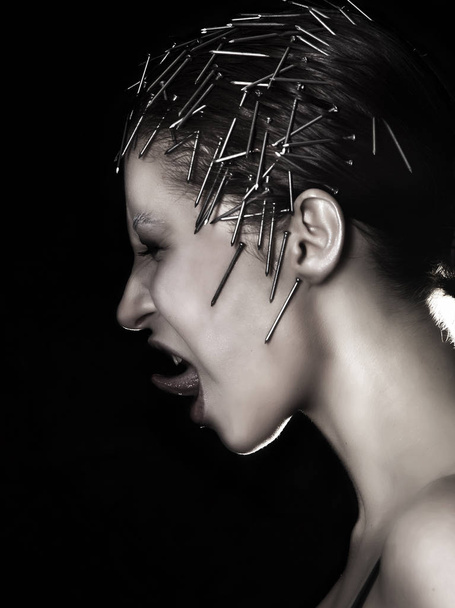 Unusual makeup of beautiful girl with nails in her head - Foto, Bild