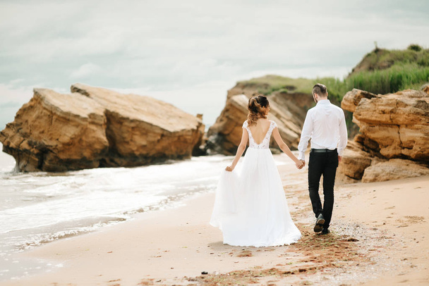 nuori pari sulhanen morsiamen kanssa hiekkarannalla
 - Valokuva, kuva
