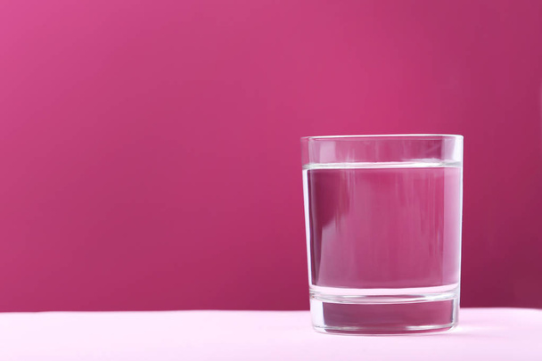 Glass with water on pink background - Фото, зображення