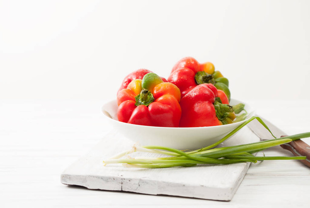 Sweet colorful raw peppers, green onions in white bowl - Foto, Imagen