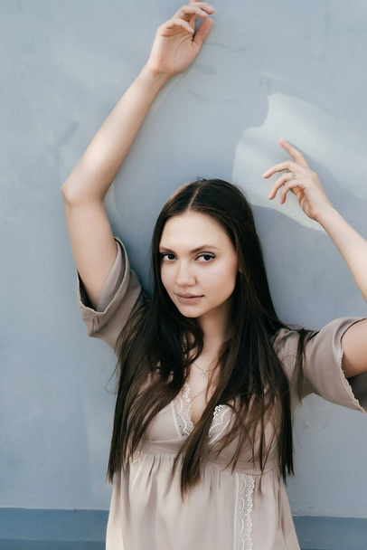 charming girl in light blouse posing against wall - Foto, Imagen