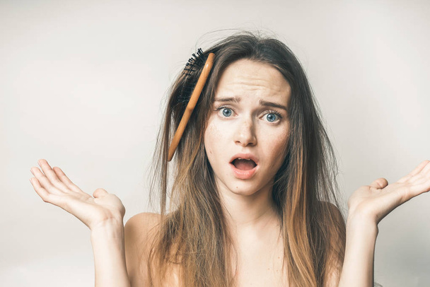 A wooden comb is stuck in the girl's hair and she does not know what to do. - Fotoğraf, Görsel