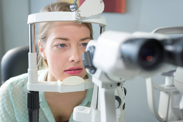 portrait of woman with head in opticians examination equipment - Foto, Imagen