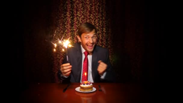 un uomo solitario celebra una vacanza, si siede da solo a un tavolo con una torta e una candela. 4k, rallentatore
 - Filmati, video