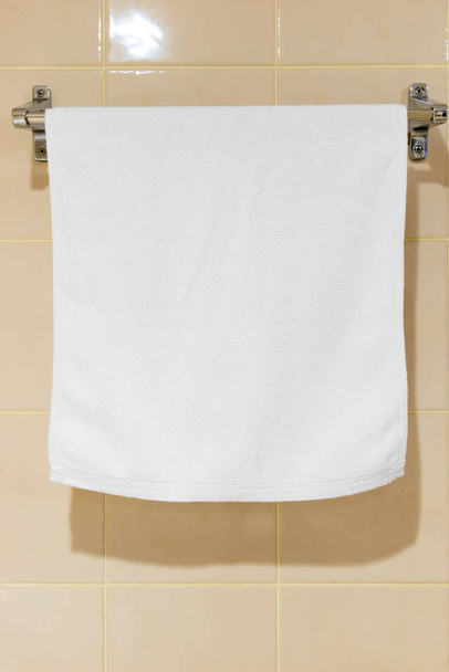 witte terry handdoek opknoping in de badkamer op de droger - Foto, afbeelding